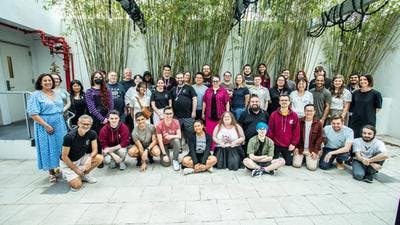 A group photo of Team Uplift at the Uplift Conference 2023. 43 people standing and kneeling for a group photo in a courtyard surrounded by green bamboo plants, everyone is smiling.. 